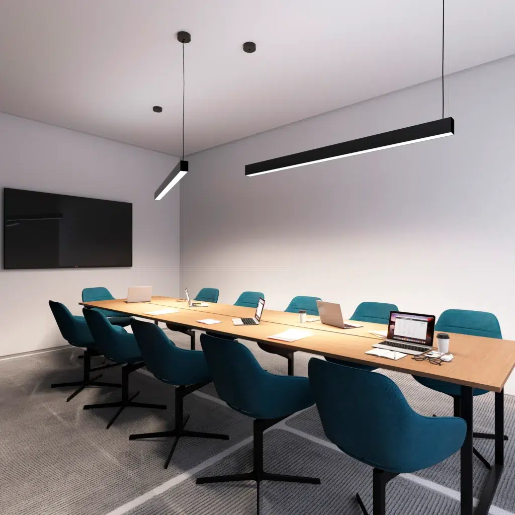 Modern conference room with a long wooden table, teal chairs, laptops, a wall-mounted TV, and hanging pendant lights.