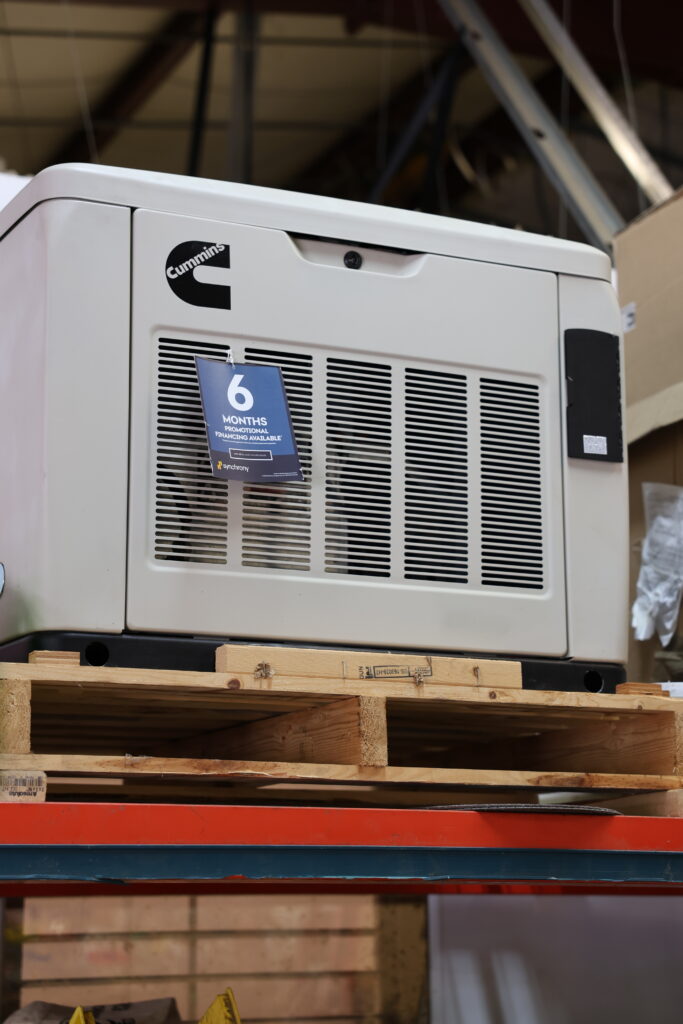 Industrial Cummins machine on a wooden pallet in a warehouse, with a blue '6 months financing available' tag hanging from the grille.